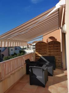 pergola na balkonie z krzesłami i stołami w obiekcie Archipel II- 30C - Appart moderne - 6 pers w Cap d'Agde +2 zdjęcia