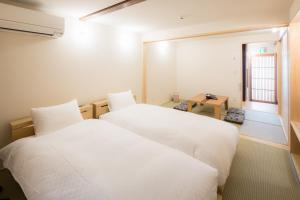 2 weiße Betten in einem Zimmer mit Fenster in der Unterkunft RESI STAY Anekoji in Kyoto