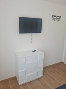 uma cómoda branca com uma televisão de ecrã plano na parede em Apartmani Jukic 3 em Kaštela