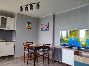 a dining room with a table and a large screen tv at Mladost 1 Apartment near the metro in Sofia