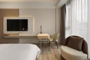 1 dormitorio con 1 cama, escritorio y TV en Gamalan Star Hotel, en Jiaoxi