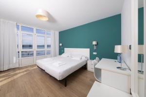 1 dormitorio con cama blanca y pared azul en Hotel Mar de Fisterra en Finisterre