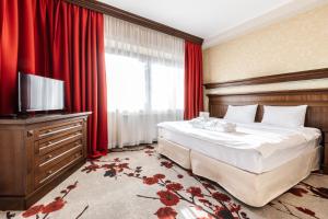 a bedroom with a bed and a television and red curtains at Hotel Crocus in Zakopane