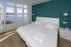 a bedroom with a white bed with a blue wall at Hotel Mar de Fisterra in Finisterre