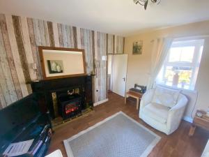 a living room with a fireplace and a chair at Daffodil Lodge in Sligo