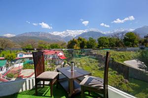 un tavolo e sedie su un balcone con vista sulle montagne di Treebo Ortus Residency a Dharamshala