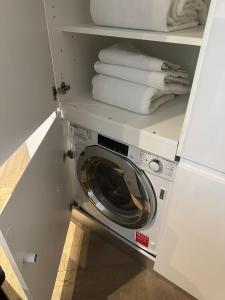 a washing machine in a white cabinet with towels at Knightsbridge Harrods Apartment in London