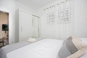 biała sypialnia z łóżkiem i oknem w obiekcie Apartman Rokov w mieście Kaštela