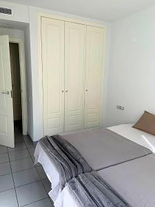 Dormitorio blanco con cama y armario en Spectacular Sea views 2 bedrooms in Villa Marina, en Benidorm