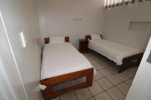 2 Betten in einem kleinen Zimmer mit weißer Bettwäsche in der Unterkunft Seagull 203 in Margate