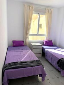 2 camas en una habitación con sábanas moradas y una ventana en Spectacular Sea views 2 bedrooms in Villa Marina, en Benidorm