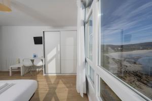 een slaapkamer met een groot raam met uitzicht op de oceaan bij Hotel Mar de Fisterra in Finisterre