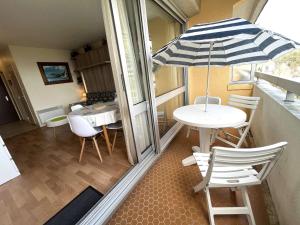stół i krzesła z parasolem na balkonie w obiekcie Studio cosy à Bénodet: plage, restos, thalasso à pied, balcon et parking privé - FR-1-481-135 w mieście Bénodet