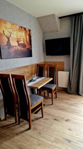 ein Esszimmer mit einem Tisch, Stühlen und einem TV in der Unterkunft Willa "KomaNcza" Szczawnica E-Apartamenty in Szczawnica