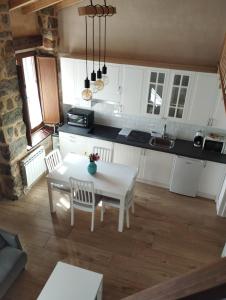 - une cuisine avec des placards blancs, une table et des chaises dans l'établissement Casas del Castillo, 4, à Ávila