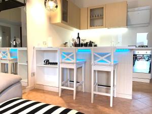 a kitchen with three stools at a kitchen counter at Bilocale 100m dal Naviglio Corsico Milano - JR HOME 1 in Corsico