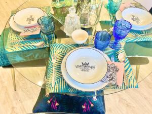 a glass table with plates and blue glasses on it at Barcelona New Apartment- Free Parking- 10 min by metro from BCN Center and Sagrada Família in Barcelona