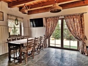 a dining room with a table and chairs and windows at Na Przypiecku in Piecki