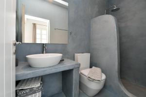 een badkamer met een wastafel, een toilet en een spiegel bij VILLA MIA PAROS in Agia Irini Paros
