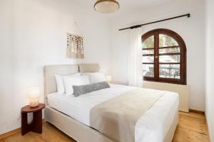 #FLH - Sun Kiss Cottage, Vourvourou في فوروفورو: غرفة نوم بيضاء مع سرير أبيض كبير ونافذة