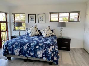 a bedroom with a blue and white bed and windows at Kindred Spirit Guest Suites with solar power in Knysna
