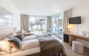 a white bedroom with a large bed and a tv at Rosfjord Strandhotel in Lyngdal