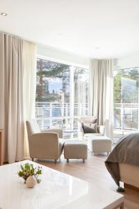 a living room with white furniture and a large window at Rosfjord Strandhotel in Lyngdal