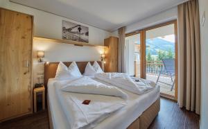 a bedroom with a large bed with a balcony at AlpenParks Hotel & Apartment Sonnleiten in Saalbach-Hinterglemm +125 photos