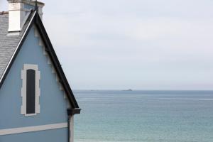 un bâtiment bleu avec l'océan en arrière-plan dans l'établissement Les Vigies by Cocoonr, à Saint-Malo