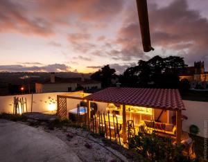 une maison avec un kiosque et un coucher de soleil en arrière-plan dans l'établissement Cozy Windmill close to the Beach, à Lourinhã