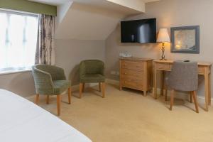 a hotel room with a desk and chairs and a television at Kings Lynn Knights Hill Hotel & Spa, BW Signature Collection in King's Lynn