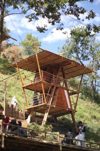 a tree house with people sitting in front of it at Bamboo Park & Resort Malino in Malino