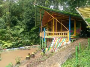a house with a colorful facade next to a river at Bamboo Park & Resort Malino in Malino