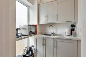 una cucina con armadi bianchi, lavandino e forno a microonde di Finest Retreats - The Den a Stamford