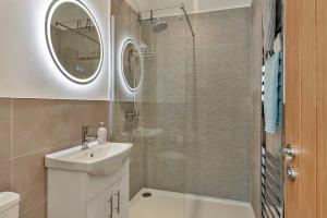 bagno con lavandino e doccia con specchio di Finest Retreats - The Den a Stamford