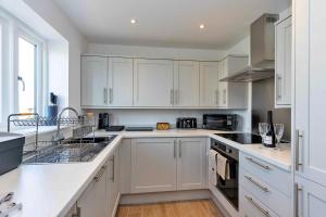 a white kitchen with white cabinets and a sink at Finest Retreats - The Holt in Stamford