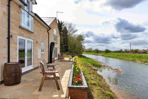 a house with a bench and flowers next to a river at Finest Retreats - The Holt in Stamford
