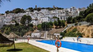a pool in front of a hill with white buildings at Casa de Luz in Casares