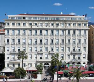 - un grand bâtiment blanc avec un panneau dans l'établissement Hôtel West End Promenade, à Nice