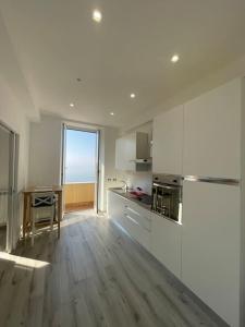 een keuken met witte kasten en een groot raam bij Appartamento Dipinto di blu- Vista Mare! in Nettuno