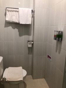 Kirei Hotel في Bonthain: حمام به مرحاض ومناشف على الحائط