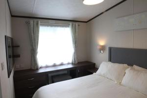 a bedroom with a bed and a desk and a window at Countryside Holiday Park by the River nr Canterbury (Pet-Friendly) in Canterbury