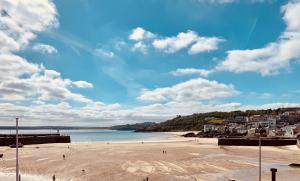 a beach with people walking on the sand at Beach House Apartment 1 - St. Ives harbour front apartment with stunning views in St Ives
