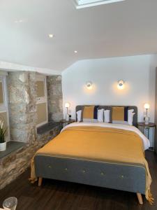 a bedroom with a large bed with a stone wall at Beach House Apartment 1 - St. Ives harbour front apartment with stunning views in St Ives