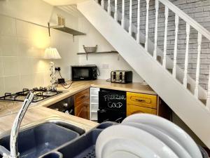 a kitchen with a sink and a stove and a staircase at Carrow Cottage in Ironbridge