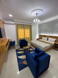 a bedroom with a bed and a blue couch and chairs at Hotel de l'Aeroport in Brazzaville