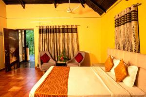 a bedroom with a bed with two chairs and a window at Farm Stay Resort - Shamirpet, Hyderabad in Hyderabad