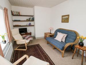 a living room with a blue couch and two chairs at 1 Hetfield Cottages in Bishops Castle