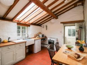 a kitchen with white cabinets and a table with a wooden tableablish at 1 Hetfield Cottages in Bishops Castle