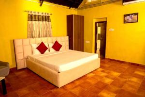 1 dormitorio con 1 cama grande en una habitación amarilla en Farm Stay Resort - Shamirpet, Hyderabad en Hyderabad